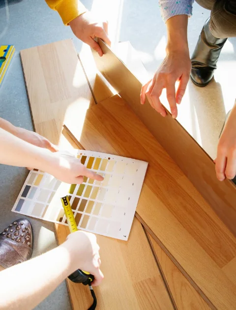 Mehrere Personen wählen Holzfarben mit Farbmusterpalette auf Holztisch aus