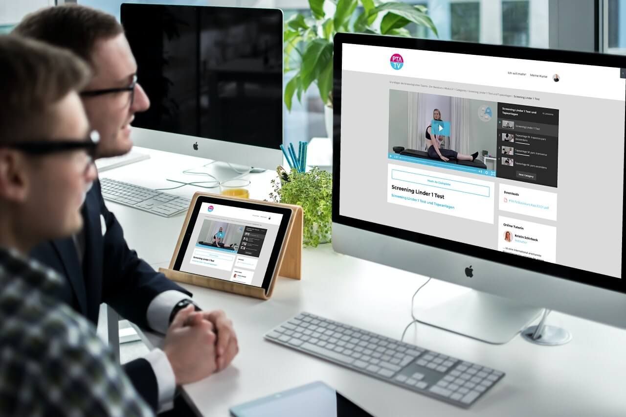 Person arbeitet mit Tablet und iMac Computer, beide zeigen PTA TV Kursplattform mit Video-Inhalten