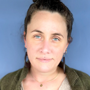 Porträt Stefanie Fischer, Frau mit dunklem Haar in grünem Shirt vor blauem Hintergrund