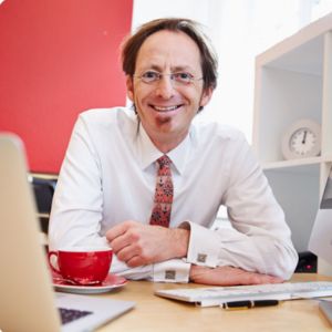 Portrait von Andreas Wucherpfennig, Mann mit Brille am Schreibtisch