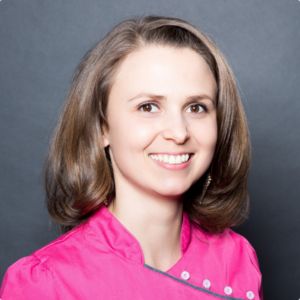 Portrait von Ann-Kathrin Klym, Frau mit Brille in weißem Oberteil