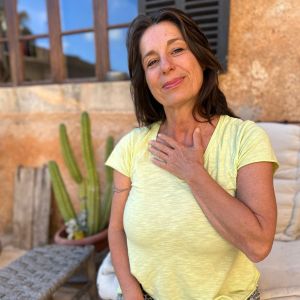 Porträt Sonja Mosick, Frau in gelbem T-Shirt vor Kaktus und Fenster