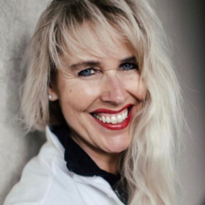 Portrait von Daniela Vollenweider, Frau mit weißen Haaren auf orange-braunem Hintergrund