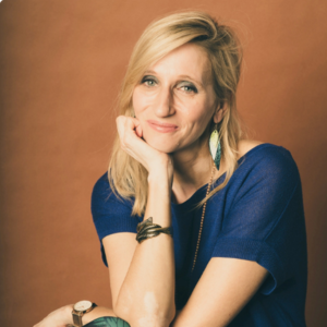Portrait von Christina Diehl, Frau mit Brille und buntem Schal vor Bücherregal