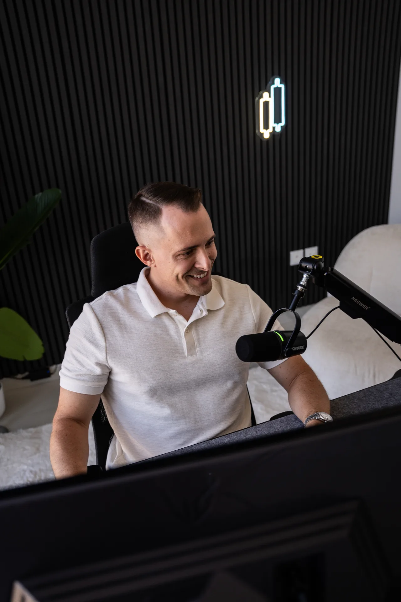Momentum Flow Strategie – Trading-Videokurs von Marco Reis 12 Mann am Schreibtisch mit Mikrofon und Kopfhörer, weißes Poloshirt, modernes Studio mit Neonlicht
