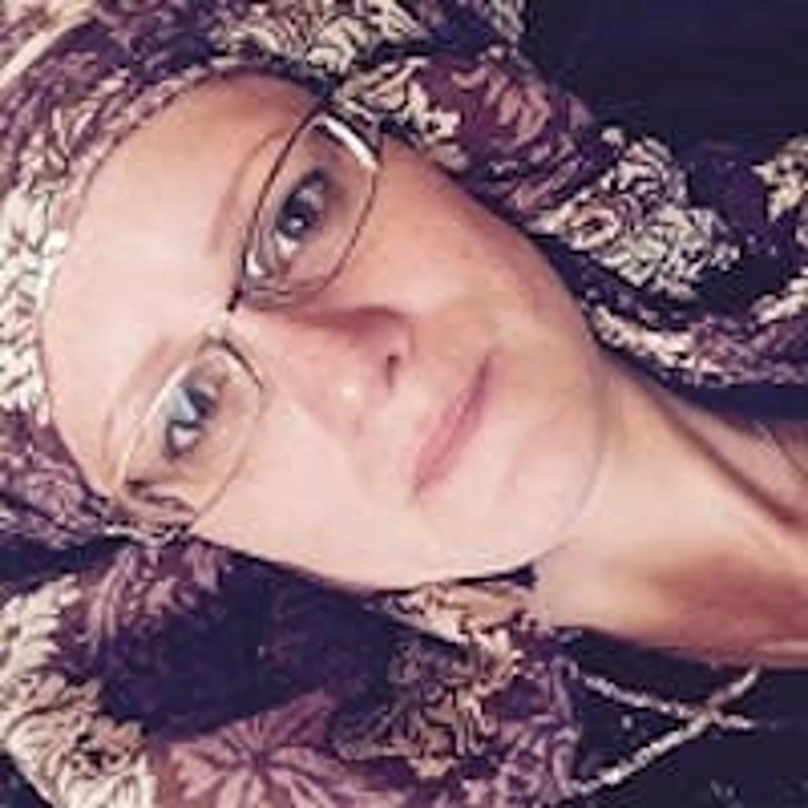 MONEY³ Mentoring – Coaching fürs Geld-Mindset von Daniel Weinstock 11 Porträt einer Frau mit Brille und beiger Kopfbedeckung vor dunklem Hintergrund