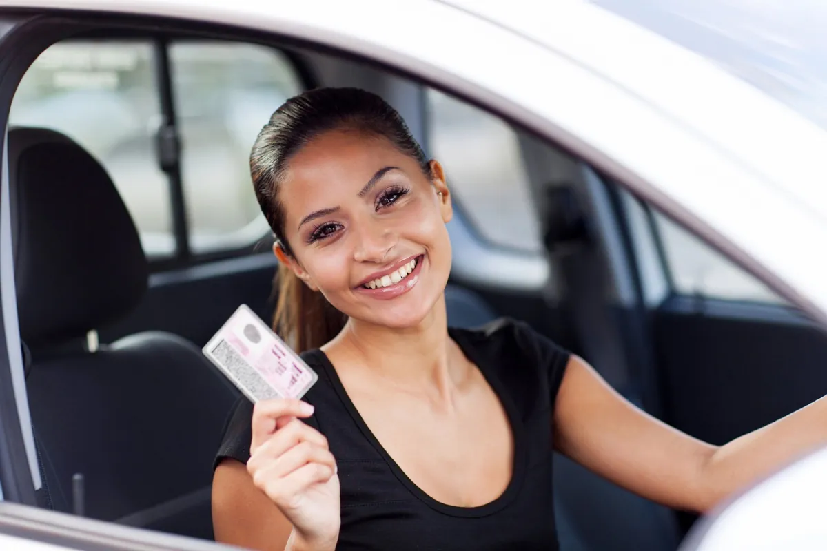 MPU-Vorbereitung online – mit Plan zurück zum Führerschein 4 Lächelnde Frau im Auto hält ihren Führerschein hoch