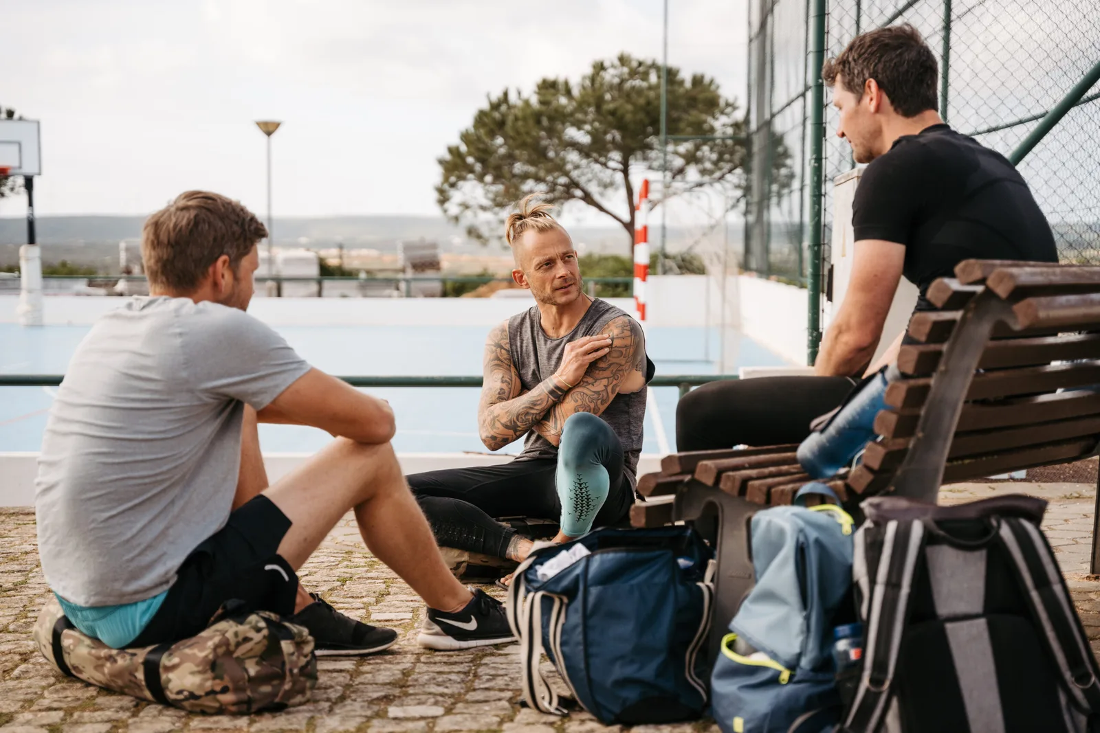 Trainer spricht mit drei Personen während Sandsacktraining-Pause am Trainingsort