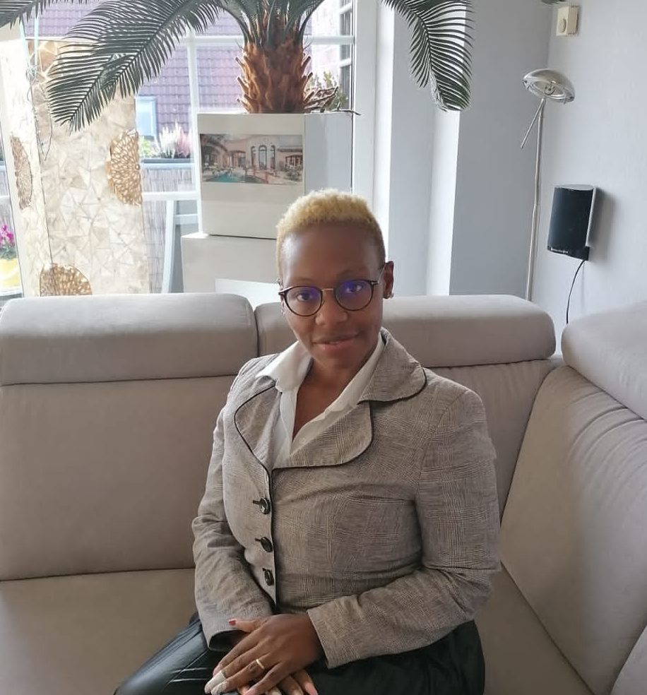 Frau mit kurzen blonden Haaren und Brille sitzt auf Sofa in modernem Wohnzimmer