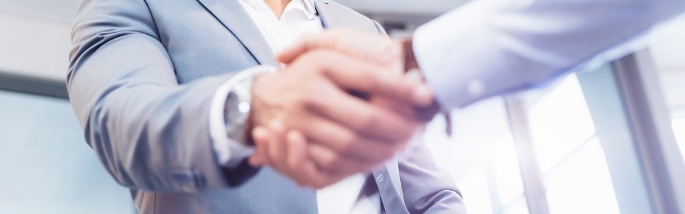 Zwei Geschäftsleute im Anzug führen Handshake durch