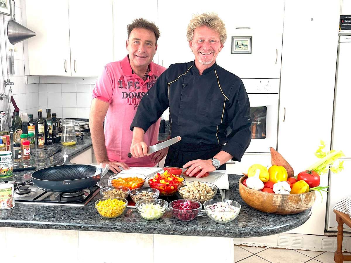 Neustart Ernährung – Basisch-Kochen-Kurs von Ralf Moll 12 Zwei Männer an Küchencounter mit verschiedenen Gemüse-Schüsseln und Pfanne beim Kochen