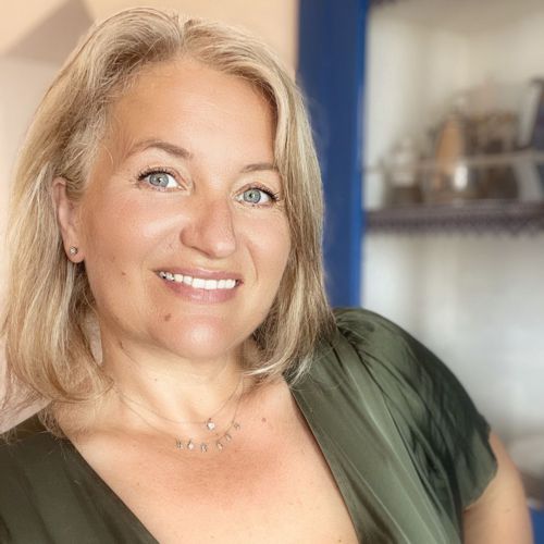 Portraitfoto von Sigrid Reutter, blonde Frau mit Halskette, grünes Oberteil, Büroumgebung