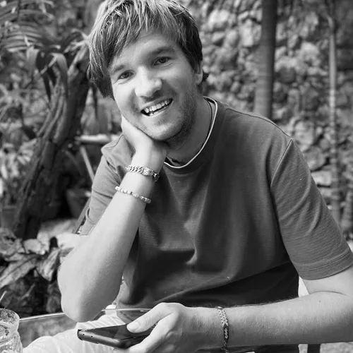 Porträt von Christoph Heuermann, lächelnder Mann mit dunklem Haar in schwarzweißem Foto vor grünem Hintergrund