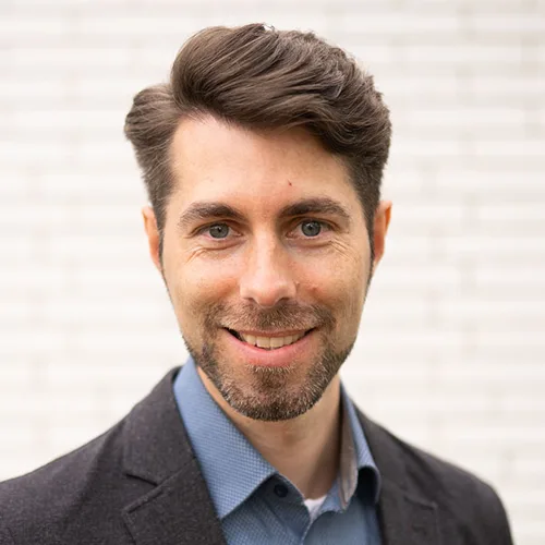 Portraitfoto von Steffen Padberg, Mann mit dunklem Haar, blauem Hemd, neutral Hintergrund