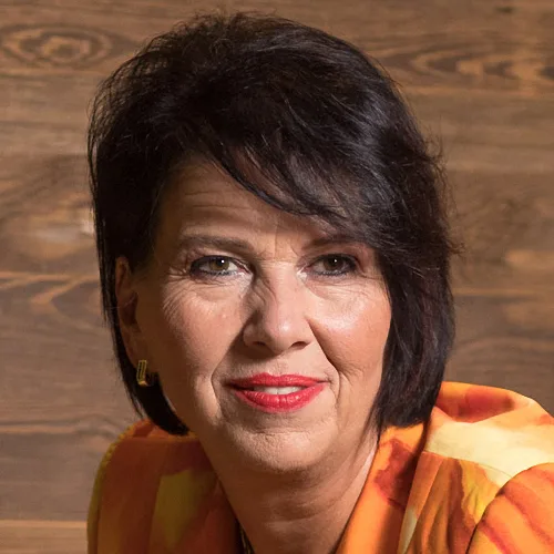 Porträt von Edith Steller, Frau mit schwarzen Haaren und rotem Lippenstift vor Holzhintergrund