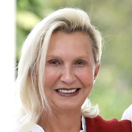 Porträt von Insha Holz, blonde Frau lächelnd vor grünem Naturhintergrund