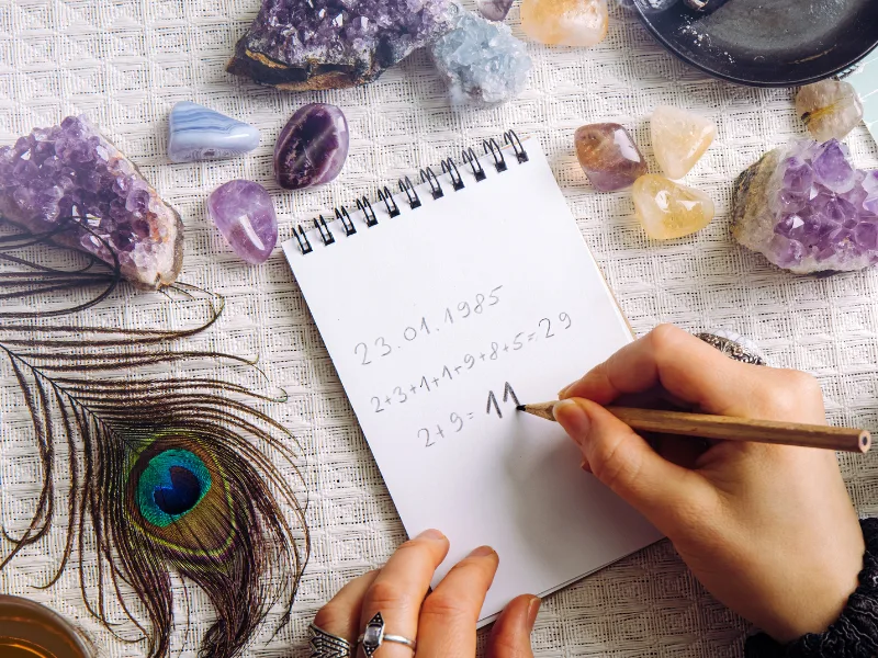 Kristalle, Feder und Notizbuch mit numerologischen Berechnungen