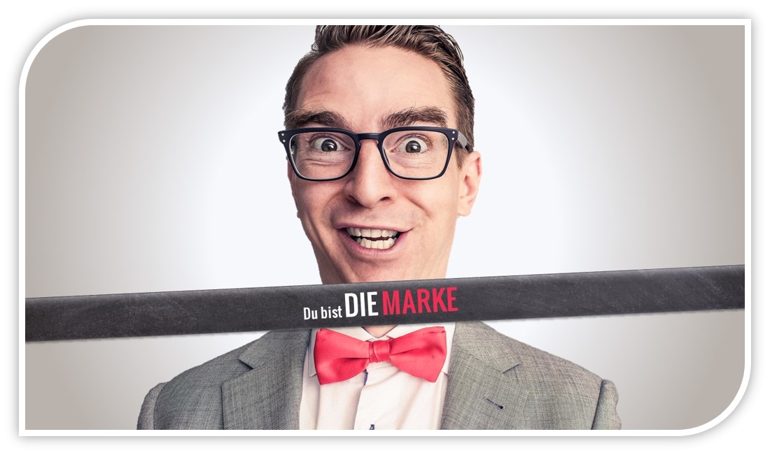 Mann mit Brille und rot-weißer Fliege, freudiger Ausdruck, Text-Banner: Du bist Die Marke
