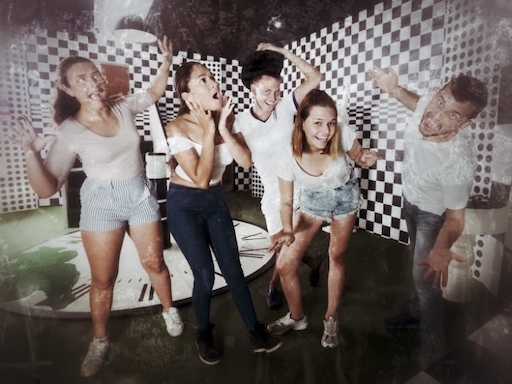 Gruppe von fünf Personen in Escape-Room mit Schachbrettmuster-Wänden