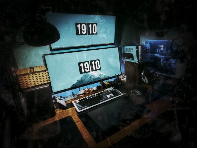Gaming-Setup mit zwei Monitoren, Tastatur und Escape-Room-Uhr 19:10
