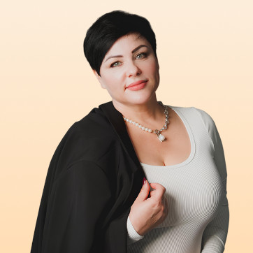 Porträt von Alla Balyuk, Frau mit schwarzem Haar, schwarzem Blazer und Perlenkette