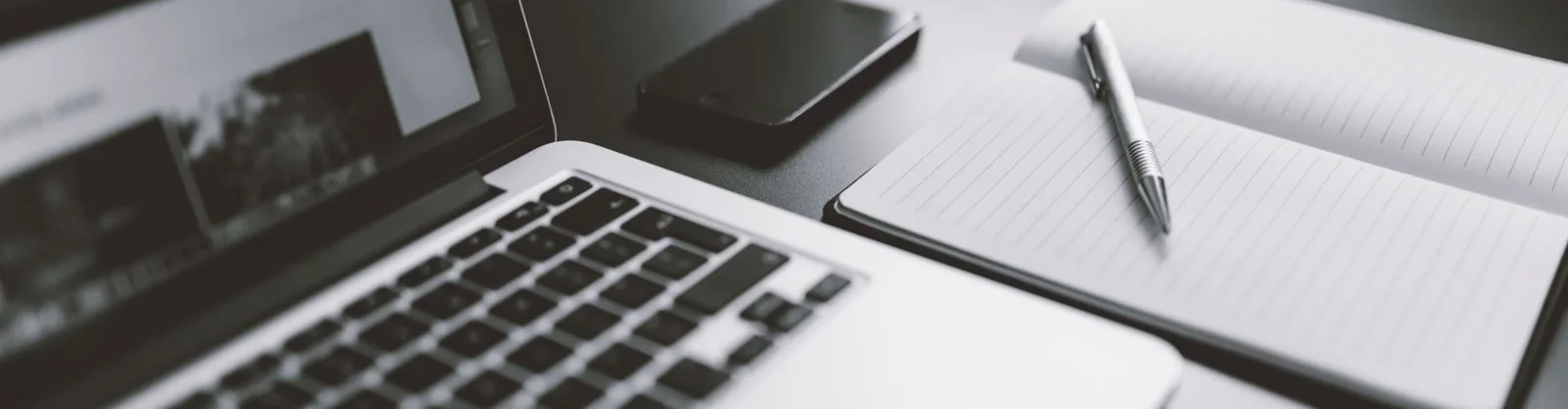 Schreibtisch mit Laptop, Notizbuch und Stift – Arbeitsplatz für Online-Training