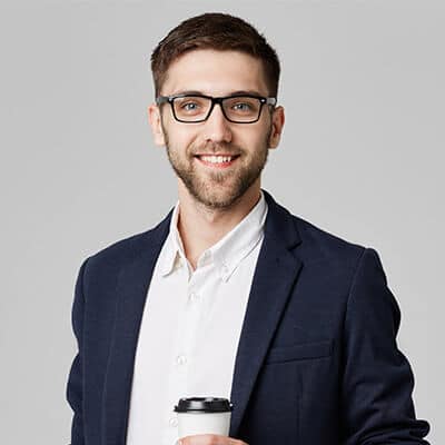 Porträt eines lächelnden Mannes mit Brille in dunklem Anzug und weißem Hemd mit Kaffeetasse