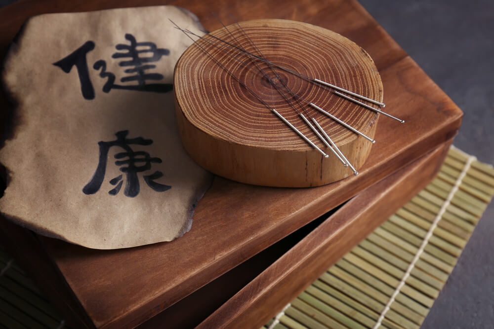 Traditionelle chinesische Akupunktur-Nadeln auf Holzständer mit chinesischen Schriftzeichen