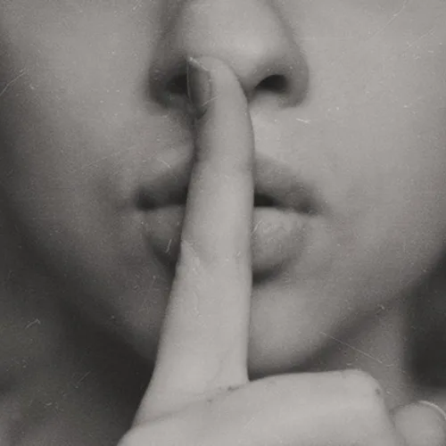 Schwarzweiß-Fotografie einer Hand vor Lippen als Schweigegeste, Datenschutz-Symbol