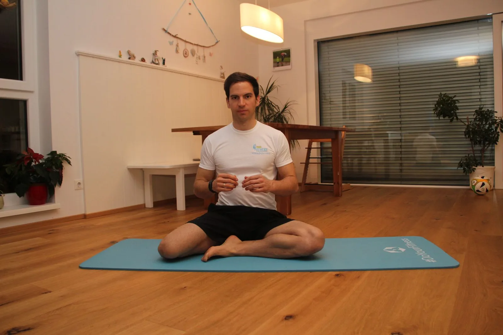 Patrick Bauer demonstriert Mobility Flow Übung auf Trainingsmatte im Wohnzimmer