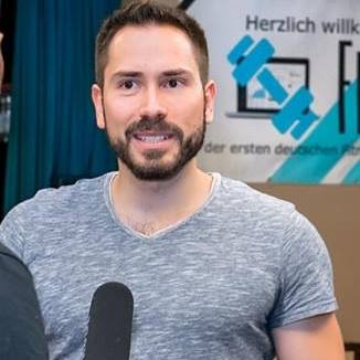 Mann mit Mikrofon vor Fitvolution Logo – Kundenstimme Jahn