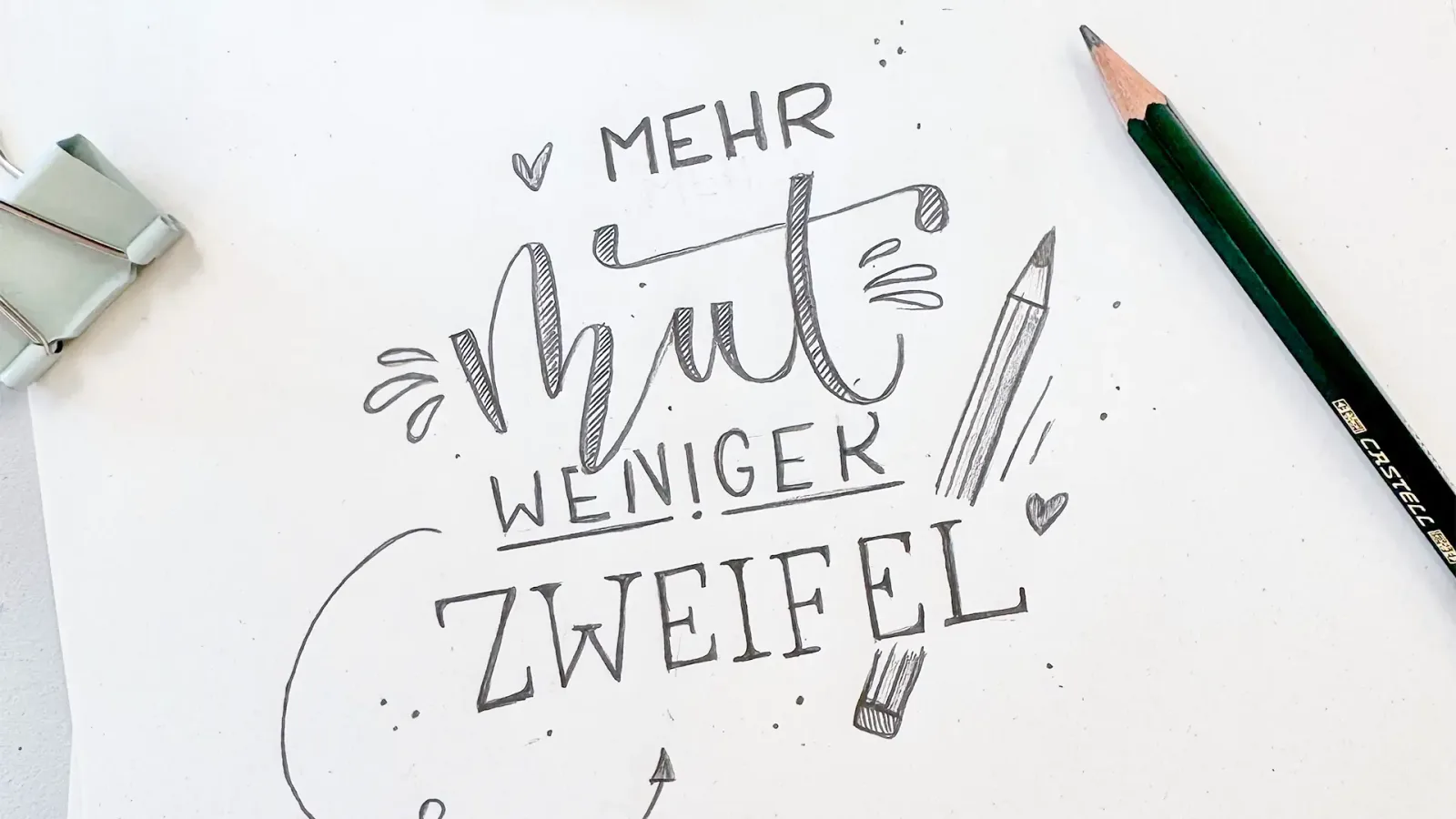 Lettering-Zeichnung mit Text 'mehr Spaß weniger Zweifel' auf weißem Papier