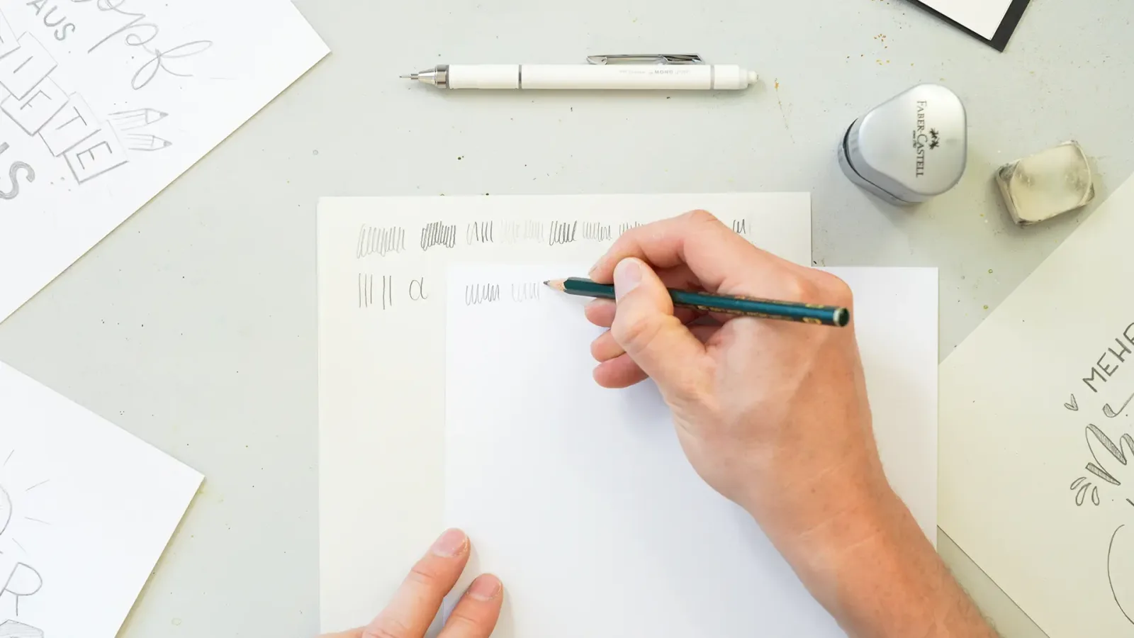 Overhead-Aufnahme von Hand beim Lettering-Training mit Stift auf Papier