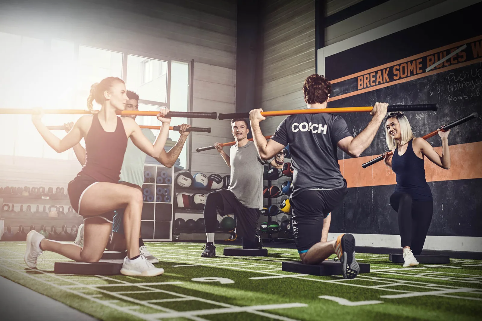 Fitnessgruppe mit Coach trainiert mit Langhantel im Fitnessstudio