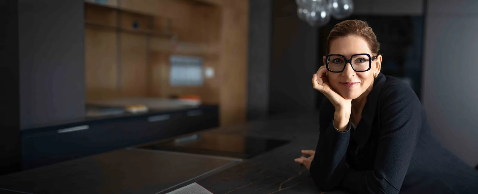 Angela Dietz in modernem Büro-Setting, lächelnd mit Hand am Kopf
