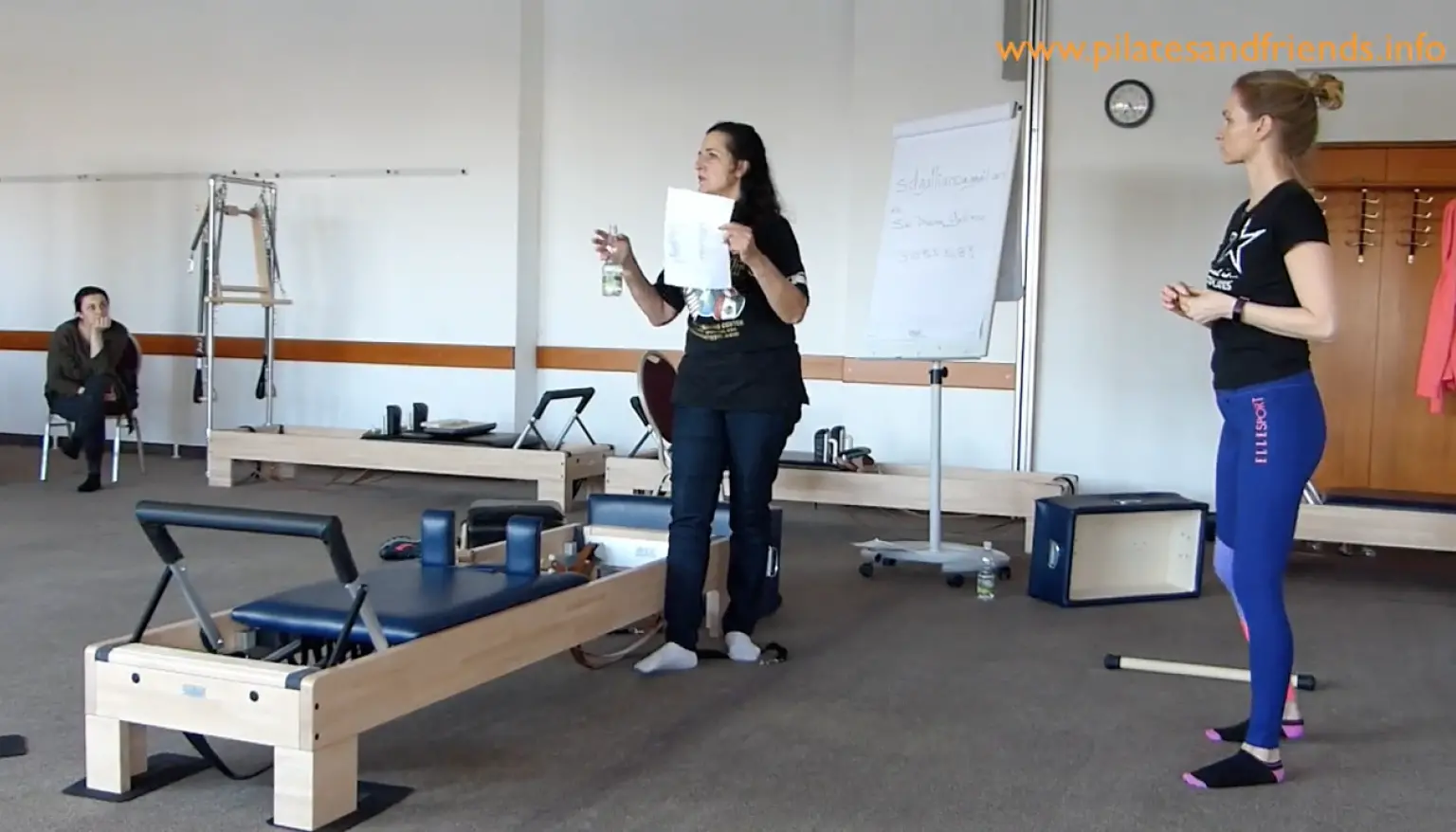 Pilates-Trainer Siri Dharma Galliano demonstriert Reformer-Übung vor Gruppe