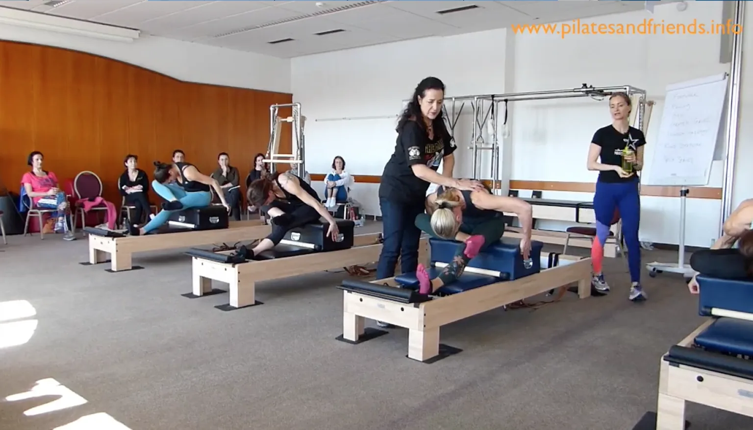 Pilates-Reformer-Kurs mit Instruktorin und Teilnehmern in Trainingsraum