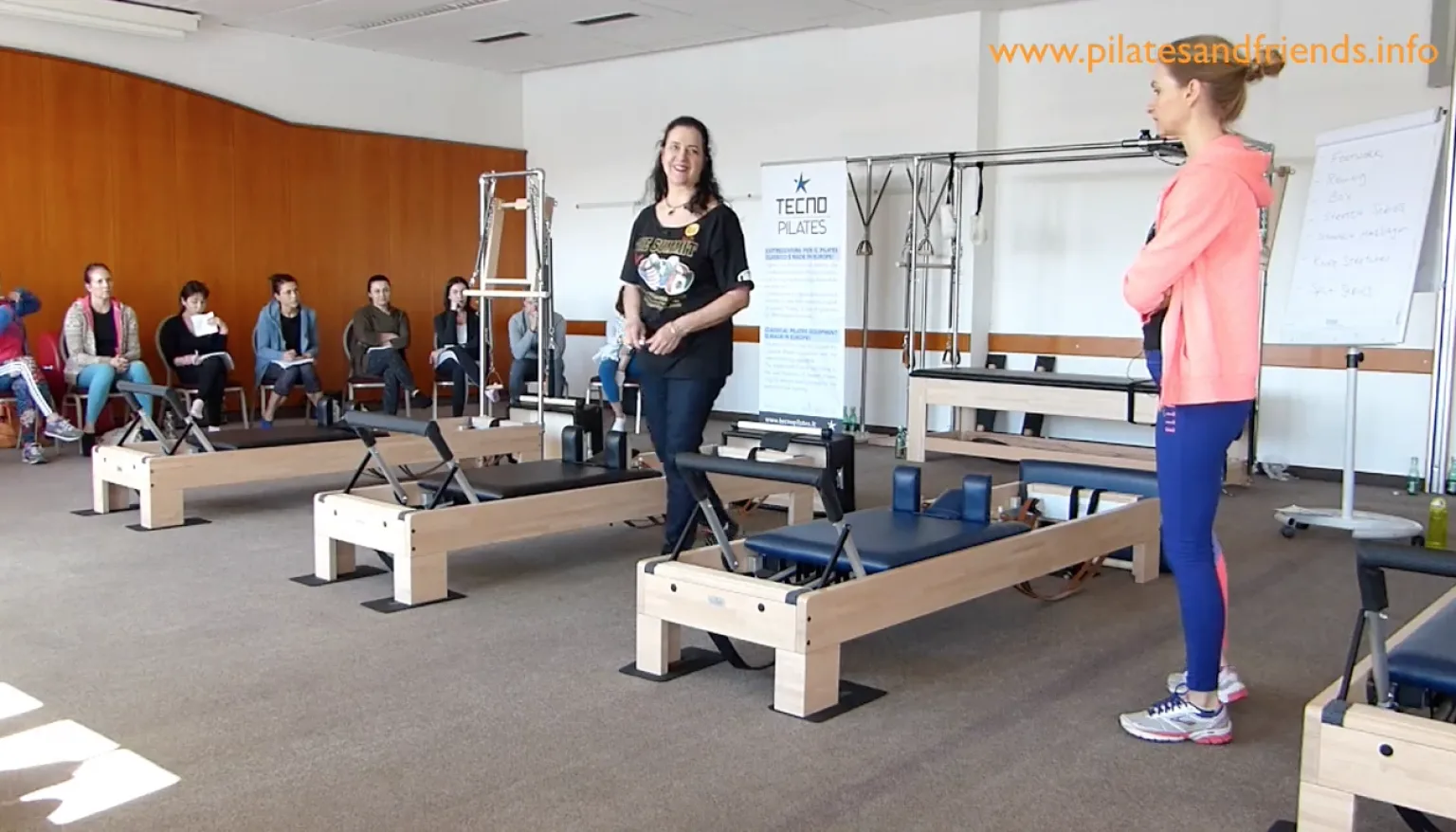 Pilates-Reformer-Kurs mit Instruktorin und Teilnehmern in Trainingsraum