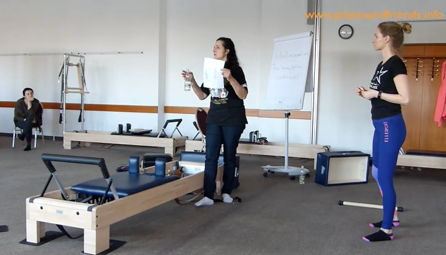 Pilates-Trainerin unterrichtet Reformer-Kurs in Fitnessstudio mit zwei Teilnehmern