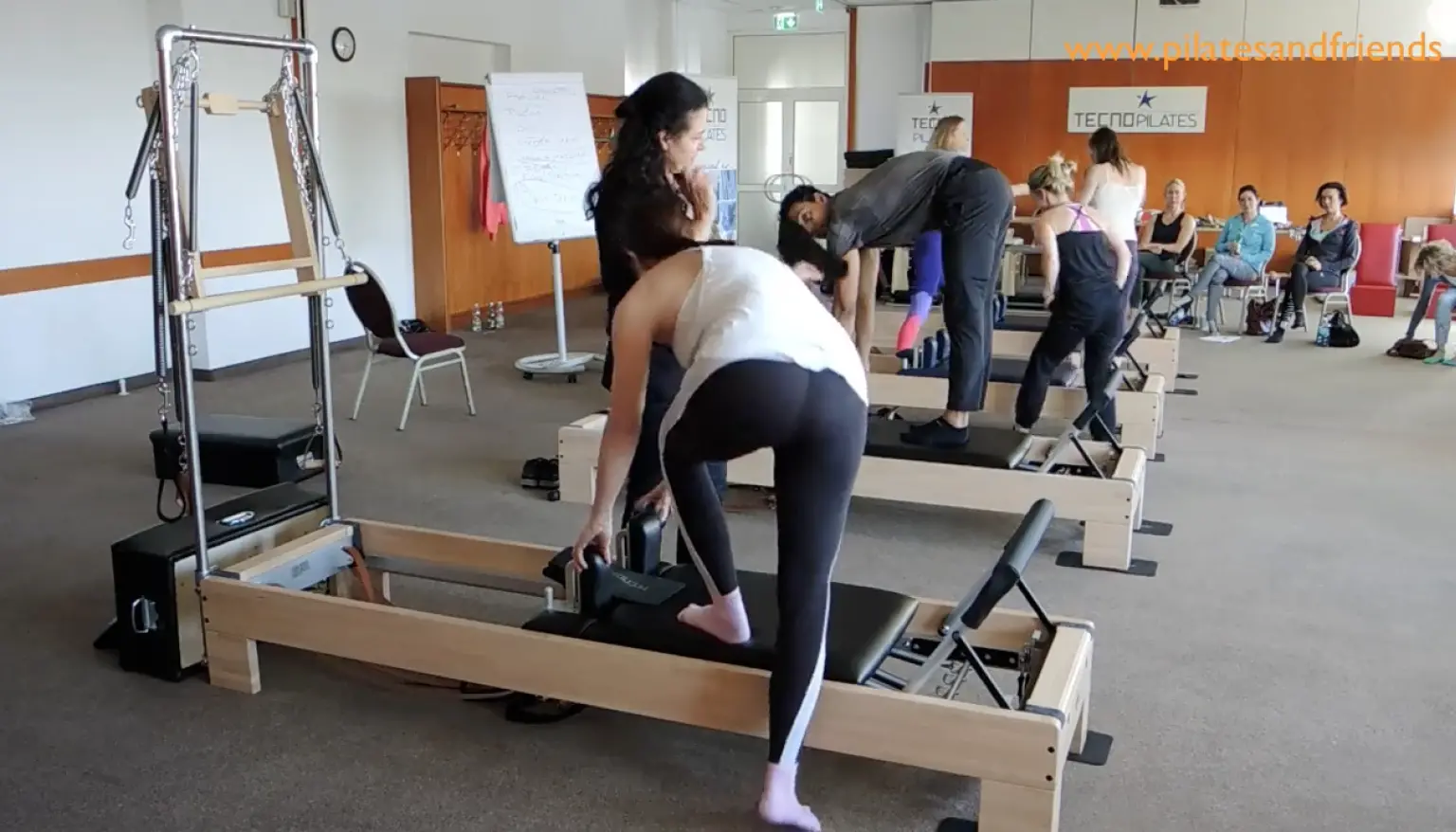 Pilates-Reformer-Kurs mit Gruppe von Teilnehmerinnen in Trainingsraum