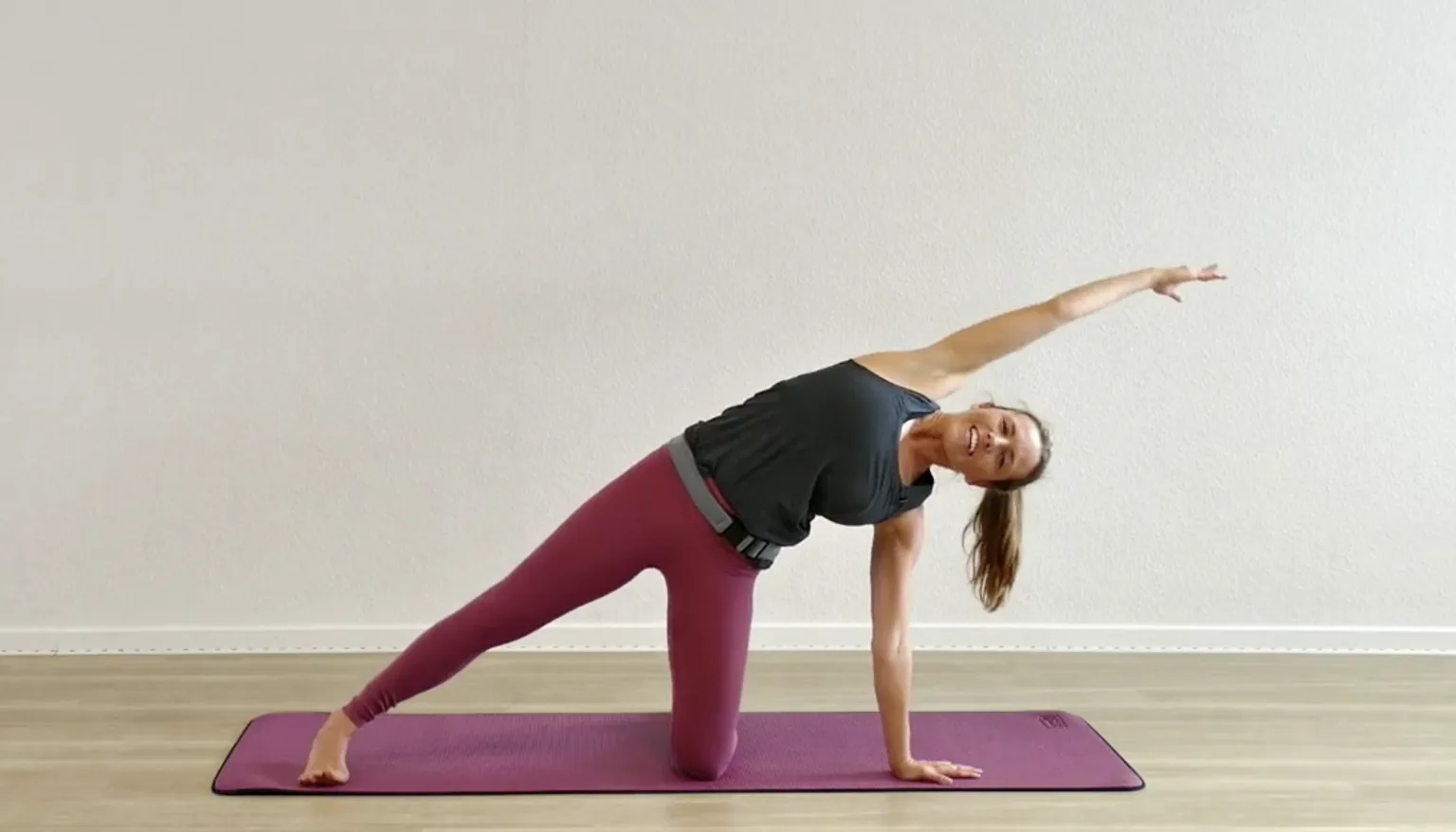 Frau in Seitenlage-Plank-Position auf violetter Yogamatte, hochauflösendes Format