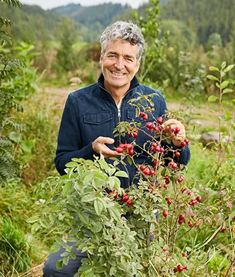 Porträt von Dr. Markus Strauss, Mann mit ergrauetem Haar hält rote Beeren in der Hand