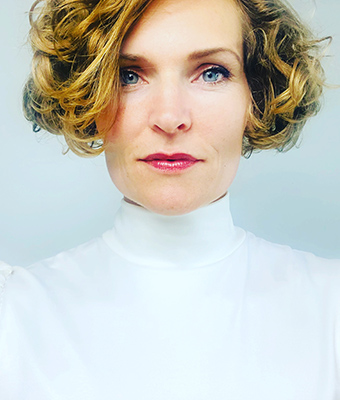 Stefanie Bruns Portrait, Frau mit blonden Haaren in weißem Rollkragenpullover