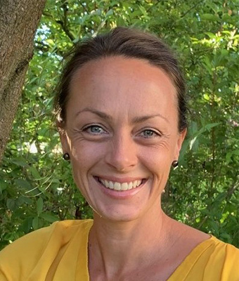 Tanja Esser Portrait, Frau mit dunklen Haaren in gelbem Shirt vor Blättern