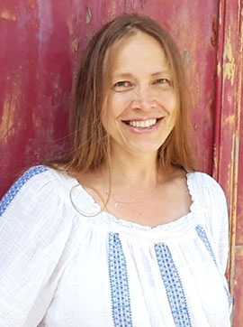 Christa Portrait, Frau mit braunen Haaren in weißem Blusenkleid vor pinkroter Wand