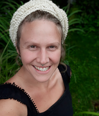 Porträt von Annina Ritter, junge Frau mit Stirnband vor grünem Hintergrund