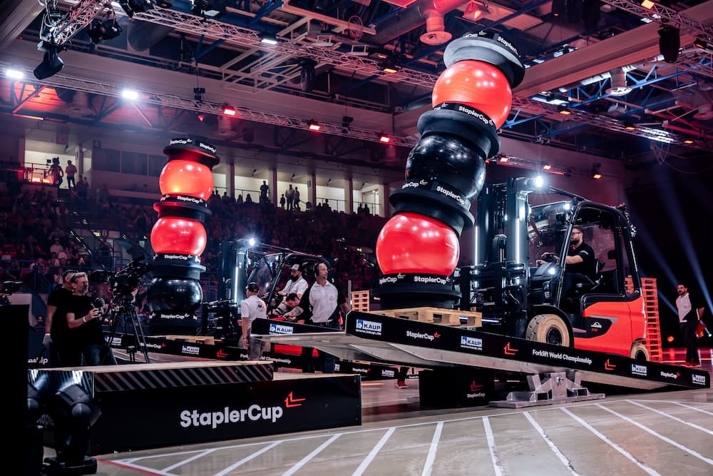 Präsentation Schulung Staplerfahrer von Christian Praetorius 9 Wettkampfszene mit Staplern und großen roten Balancierbalken auf Bühne bei StaplerCup Finals