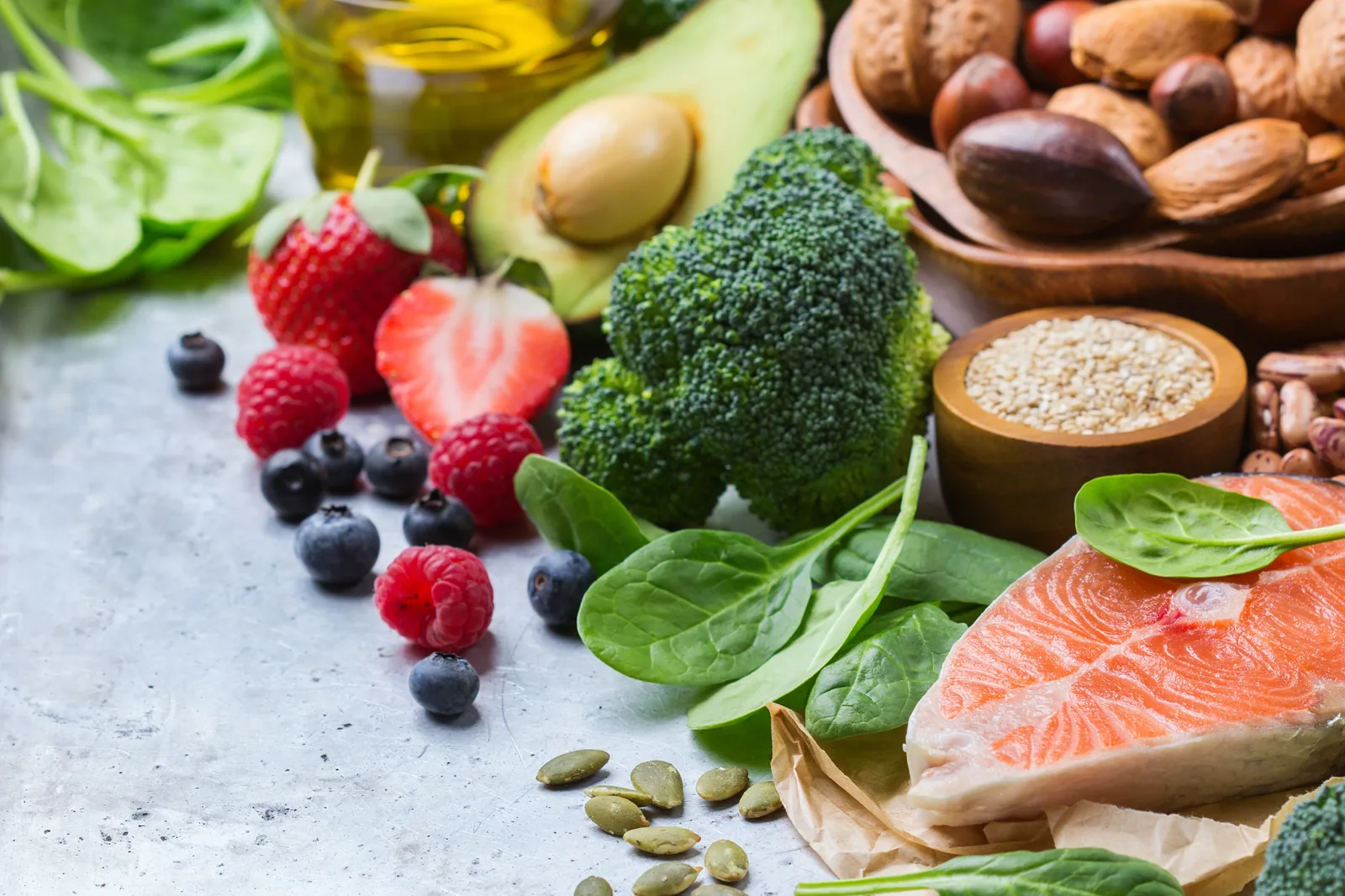 Flach gelegte Healthy-Food-Komposition mit Lachs, Brokkoli, Beeren, Nüssen, Avocado und Olivenöl