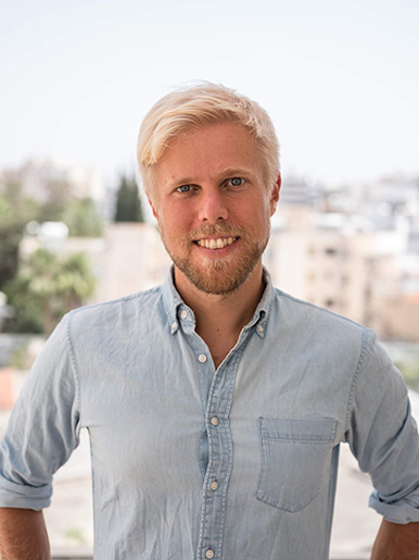 Privates Coaching mit Tim – Einzelgespräche für innere Ruhe 1 Portrait von Tim, blonder Mann mit Bart in hellblauem Jeanshemd vor unscharfem Stadtpanorama
