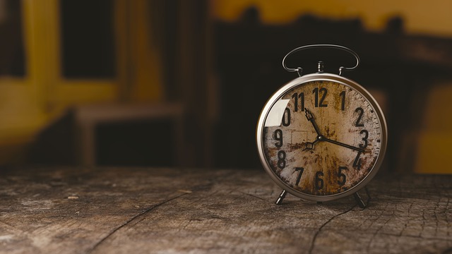 Alte analoge Wecker-Uhr auf Holztisch mit unscharfem Hintergrund